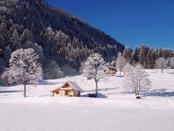 House on snow covered landscape against sky