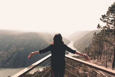 Rear view of man looking at mountain range against sky