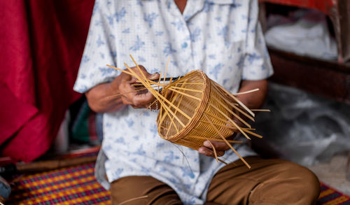 Midsection of man making wicker in workshop