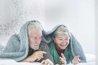 Smiling senior couple lying on bed at home