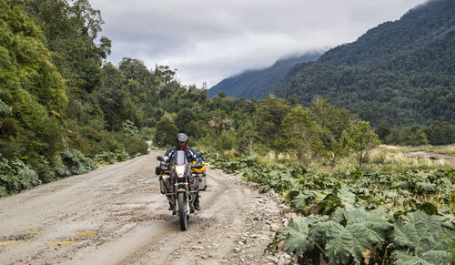Man driving on a touring motorbike gravel road on carretera austral