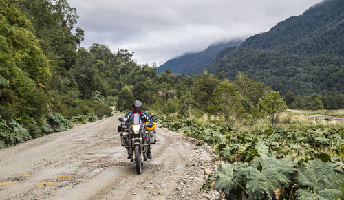 Man riding bicycle on road against mountains