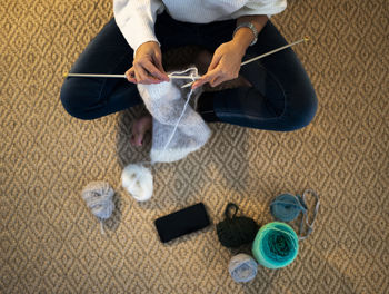 Midsection of woman knitting wool at home