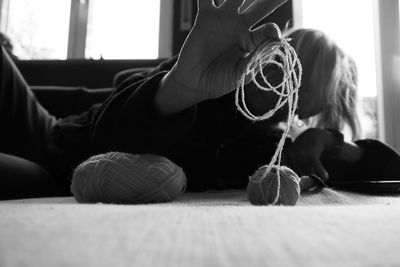 Surface view of woman holding ball of wool lying on floor at home