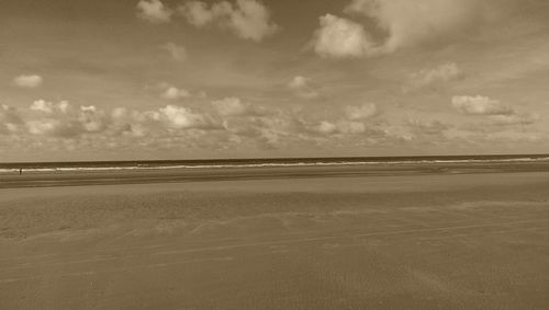 Scenic view of beach against cloudy sky