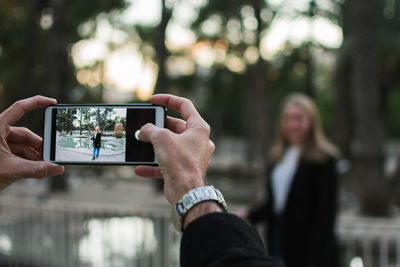 Midsection of woman photographing with mobile phone