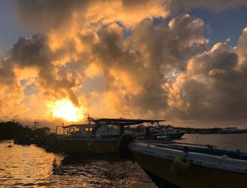 Boats moored on sea against sky during sunset