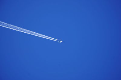 Low angle view of airplane flying against clear blue sky