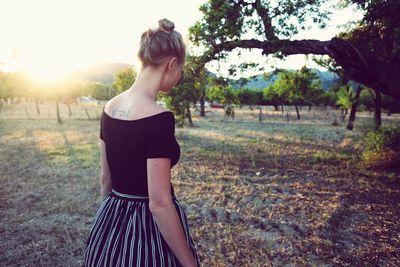Rear view of young woman standing on field