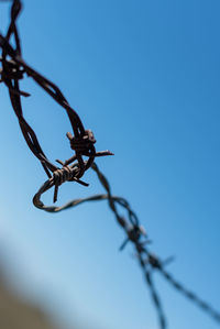 Low angle view of barbed wire against clear sky