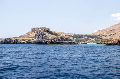 Rock formation by sea against clear sky