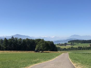 Road amidst field against clear sky