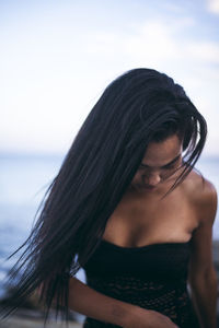Black multiracial woman lifestyle portrait by the ocean in a swimsuit