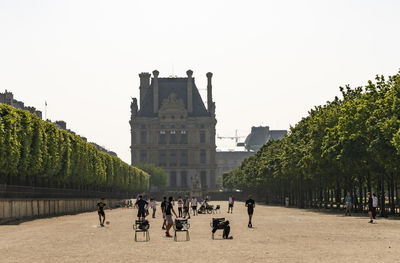 Group of people playing football in the park in front of building in paris, france