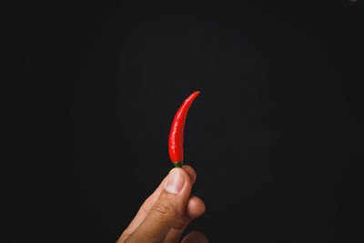 Close-up of hand holding ice cream against black background