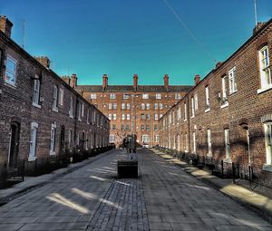 People walking on footpath amidst buildings against sky