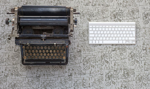 Directly above shot of old typewriter by computer keyboard on table