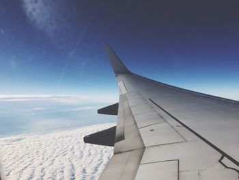 Cropped image of airplane flying over landscape against sky