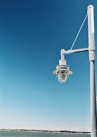 Low angle view of telephone pole against clear blue sky