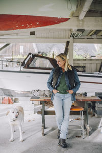 Mature woman with hands in pockets looking at dog in garage