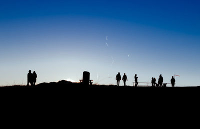 Silhouette people walking on landscape against clear sky