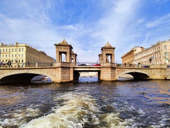 Arch bridge over river against cloudy sky