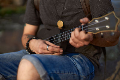 Midsection of man playing guitar