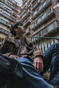 Low angle view of men sitting on sidewalk in city