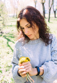 Portrait of a young brunette woman in spring in a park with dandelions