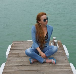 Young woman sitting on pier over sea