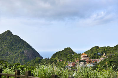 Scenic view of townscape by mountains against sky