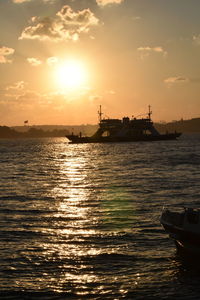 Silhouette ship in sea against sky during sunset