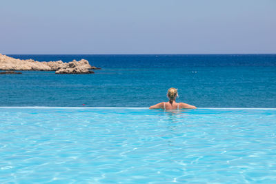Woman in swimming pool against sea