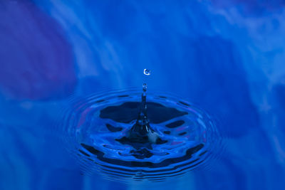 Close-up of drop falling on blue water