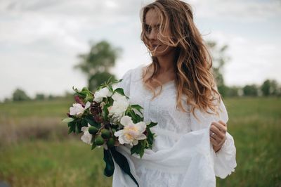 Bride holding bouquet while standing on field