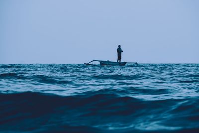 Silhouette man in sea against clear sky