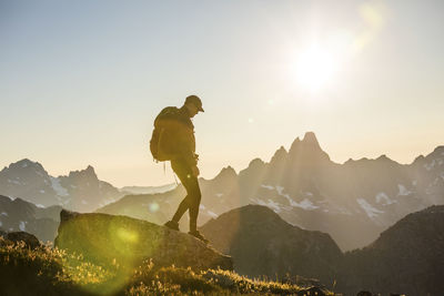 Backpacker hiking on mountain summit during sunset.