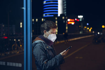 Man using mobile phone on street at night