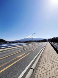 Road by mountain against clear blue sky