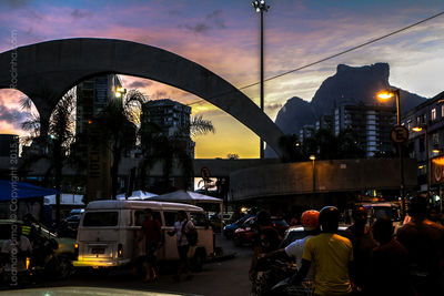 People on street in city against sky during sunset