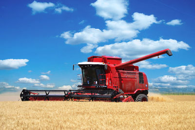 Combine harvester on field against sky