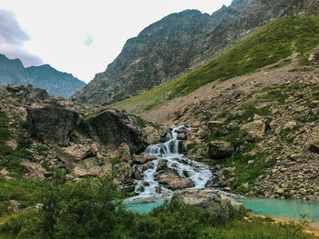 Scenic view of waterfall against mountains