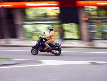 Man riding motor scooter on road