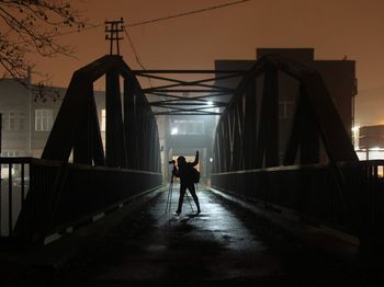 Silhouette person with camera standing on suspension bridge