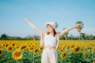 Rear view of woman standing on sunflower field