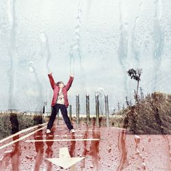 Double exposure image on girl standing on wet footpath and condensed glass