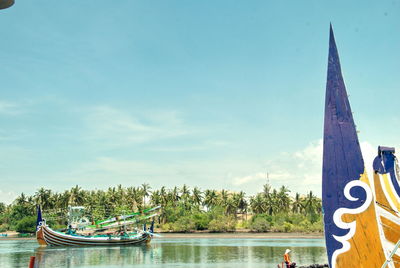 View of boats in river against cloudy sky