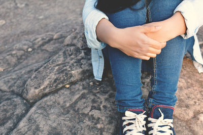 Midsection of woman sitting on rock