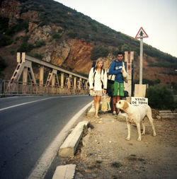 Rear view of woman with dog walking on road