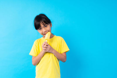 Girl eating ice cream against blue background